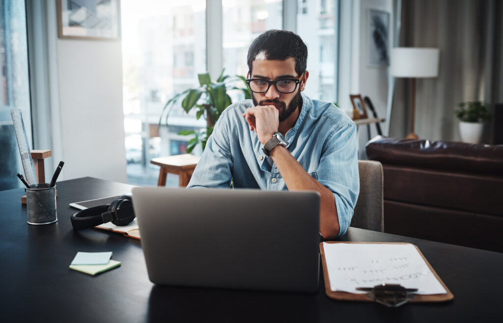 Shot of a young man using his laptop while working from home