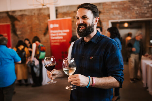 Man holding two glasses of wine at Canadians Connected: Edmonton