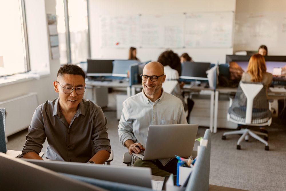 Two men collaborating over a laptop at work